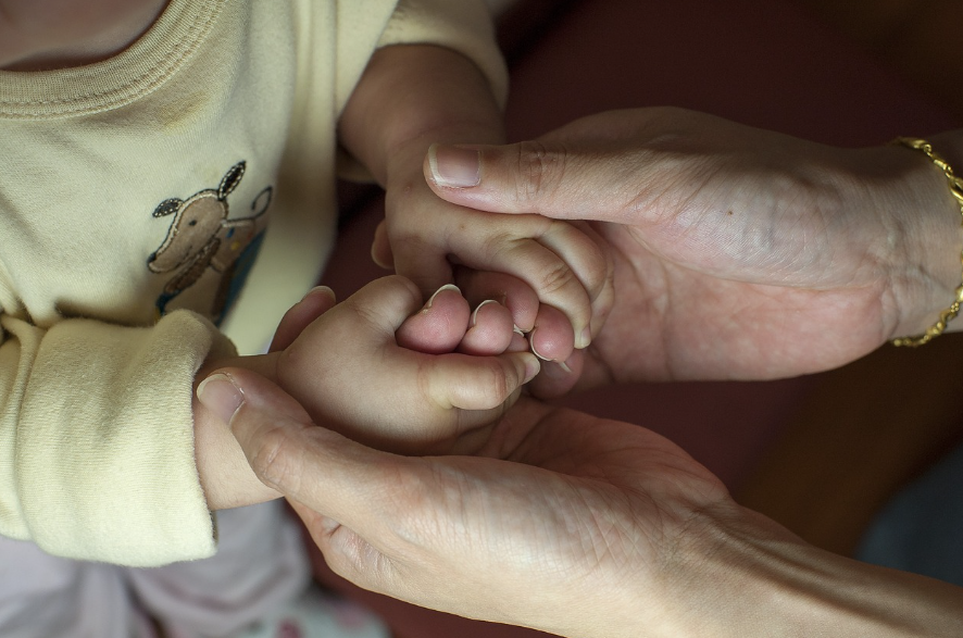 아기와 엄마가 손을 마주잡고있다