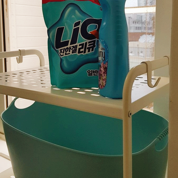 쉐어하우스 세탁실 선반 위에 깔끔하게 정리된 민트색 세탁 바구니와 세제통 전경