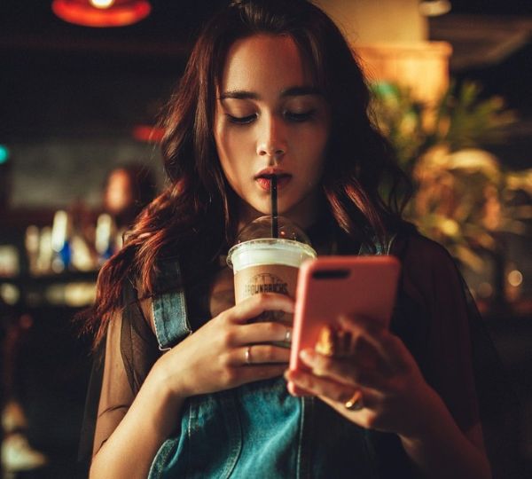 커피를 마시면서 핸드폰 문자를 살피는 여성