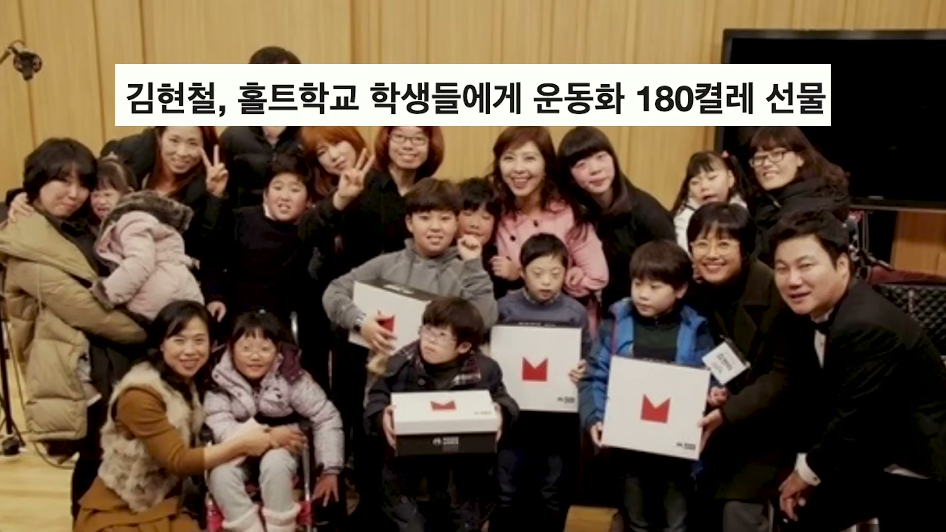 홀트학교 학생들과 가족들이 단체로 모여 사진을 찍은 장면. 아이들이 빨간색 신발 박스를 들고 있고 김현철도 함께 있다.