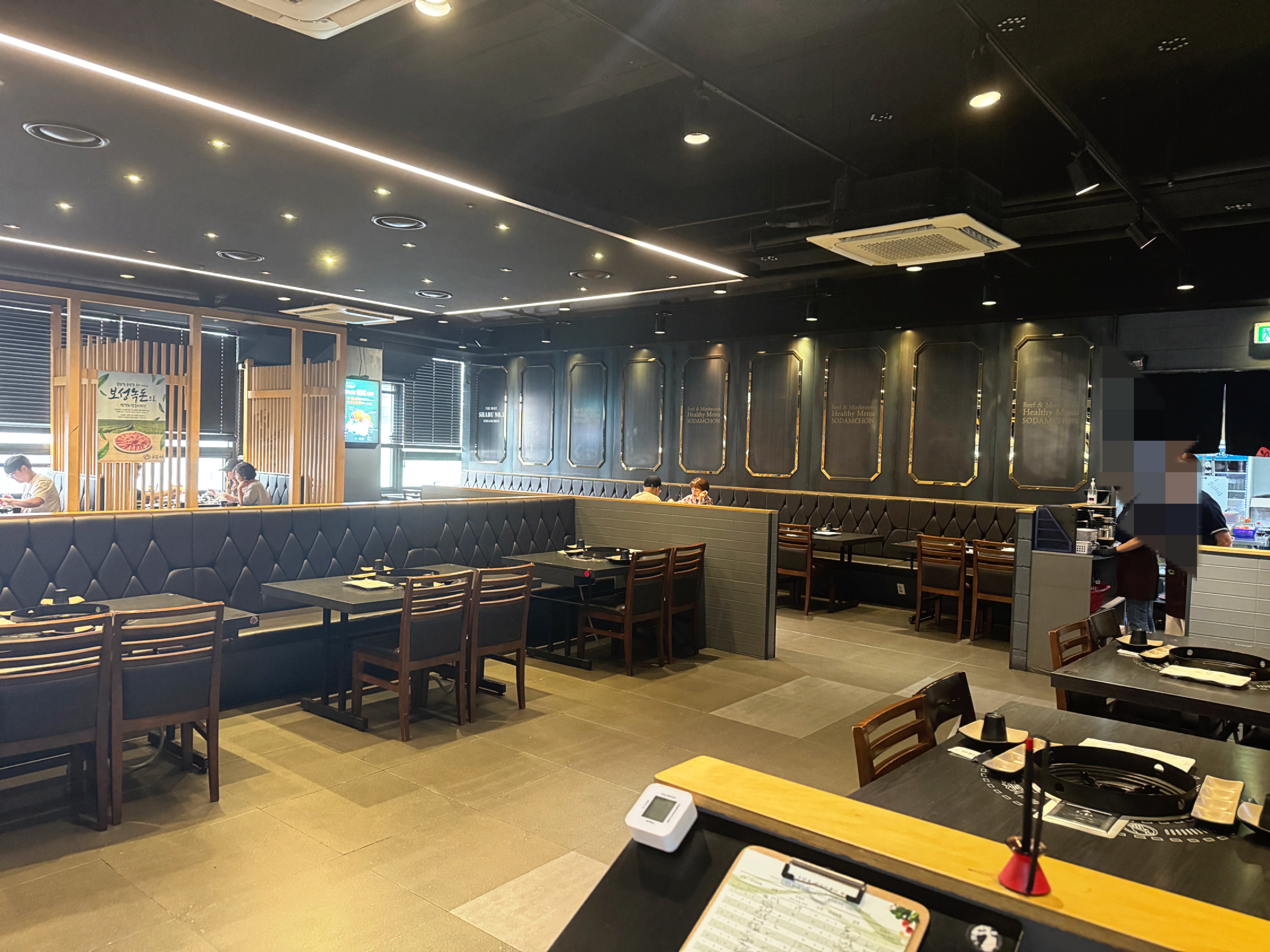 소담촌 김포한강신도시점 내부 전경 – 블랙톤 인테리어와 넓은 테이블 배치, 여유 있는 좌석 공간이 보이는 김포 소담촌 샤브샤브 매장 전경