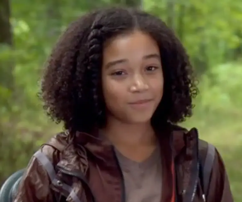 초롯숲 앞 곱슬머리의 흑인소녀가 미소지으며 서있는 모습