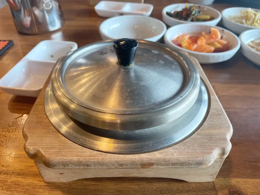 나무 받침대에 스테인리스 솥에 솥밥이 나오는 모습