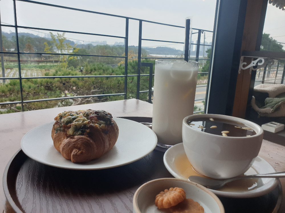 대파 크로아상, 가을밤 라테, 계피 생강차가 보인다. 그 뒤로 밭뷰가 보인다.