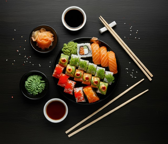 검정 식탁에 초밥 한세트가 있다. 검정 둥그런 접시에 연어초밥, 와사비가 가득하고 주변엔 간장, 와사비, 생강접시가 있다.