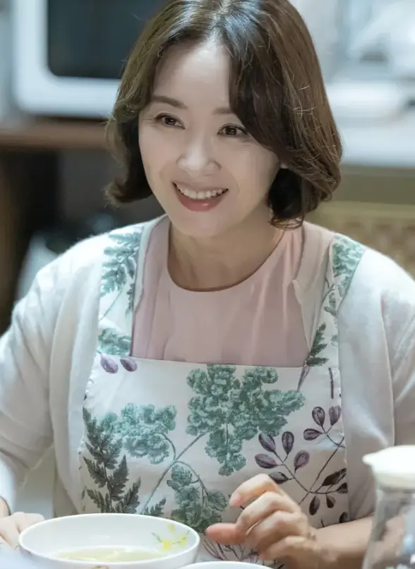 재벌X형사-
초록색 나뭇잎이 그려진 흰앞치마 안 흰 가디건 안 분홍색 스웨터를 입고 갈색단발머리에 미소짓고 있는 고미숙