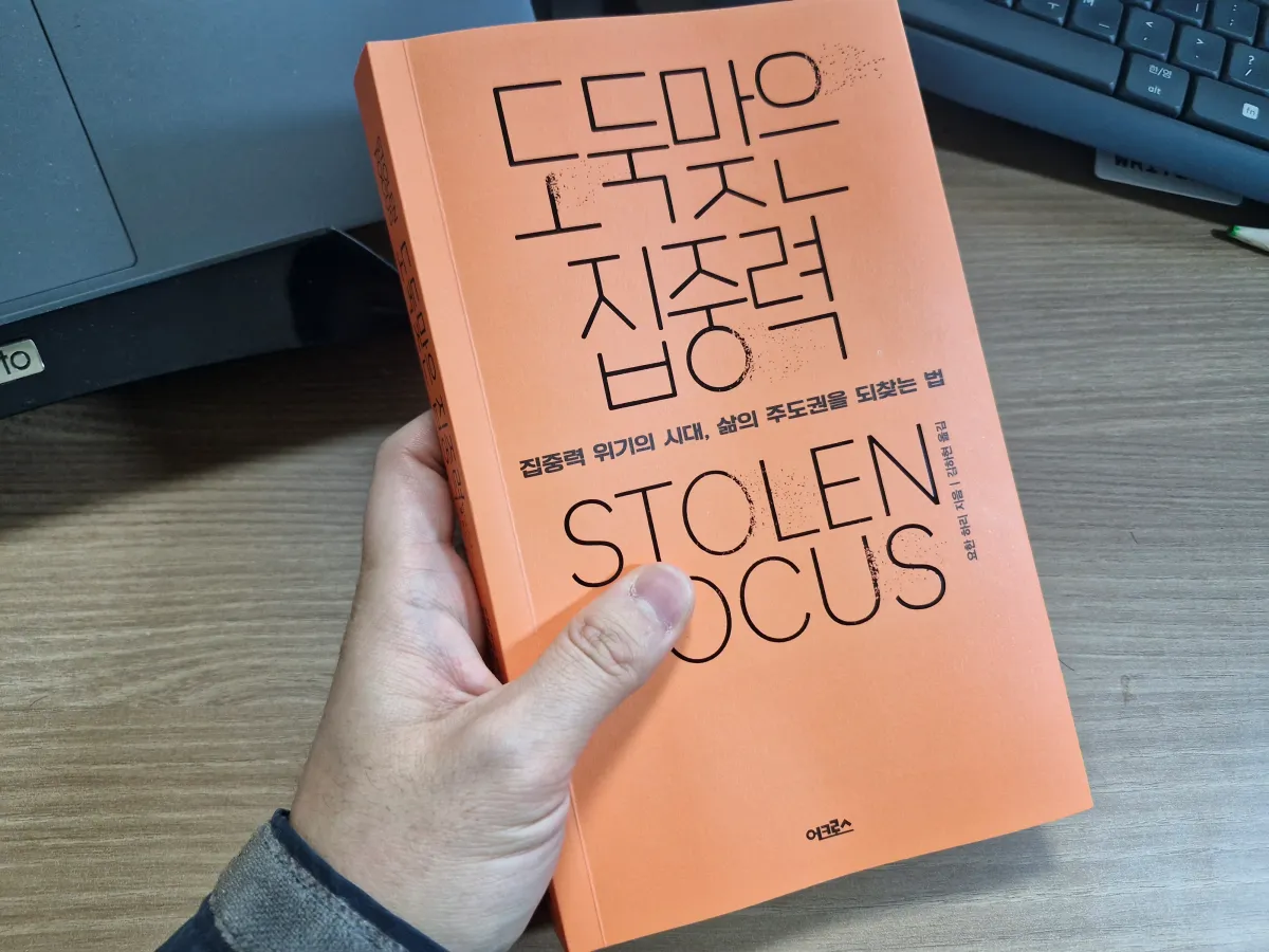 주황색-책을-들고있는-남성의-손