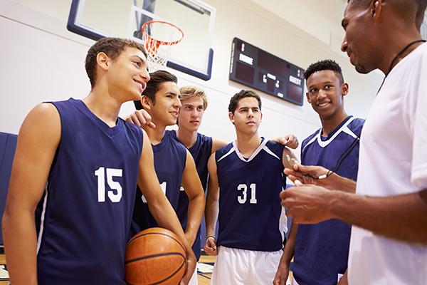 Youth basketball coach giving emotional pep talk to team in gym, fostering trust and positive mindset