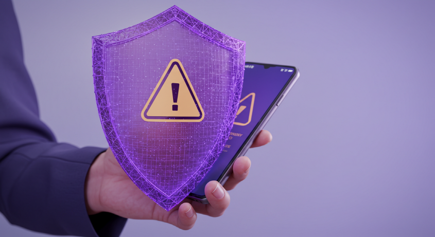 가상자산 사기 예방을 상징하는, 경고 화면이 뜬 스마트폰을 보호하는 방패