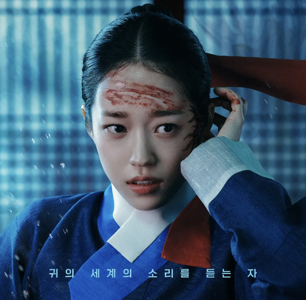 드라마 '동궁' 포스터. 파란색 한복을 입은 생강의 이마에 핏자국이 선명하며, 겁에 질린 표정으로 어딘가를 바라보고 있습니다. 하단에는 '귀의 세계의 소리를 듣는 자'라는 문구가 있습니다.