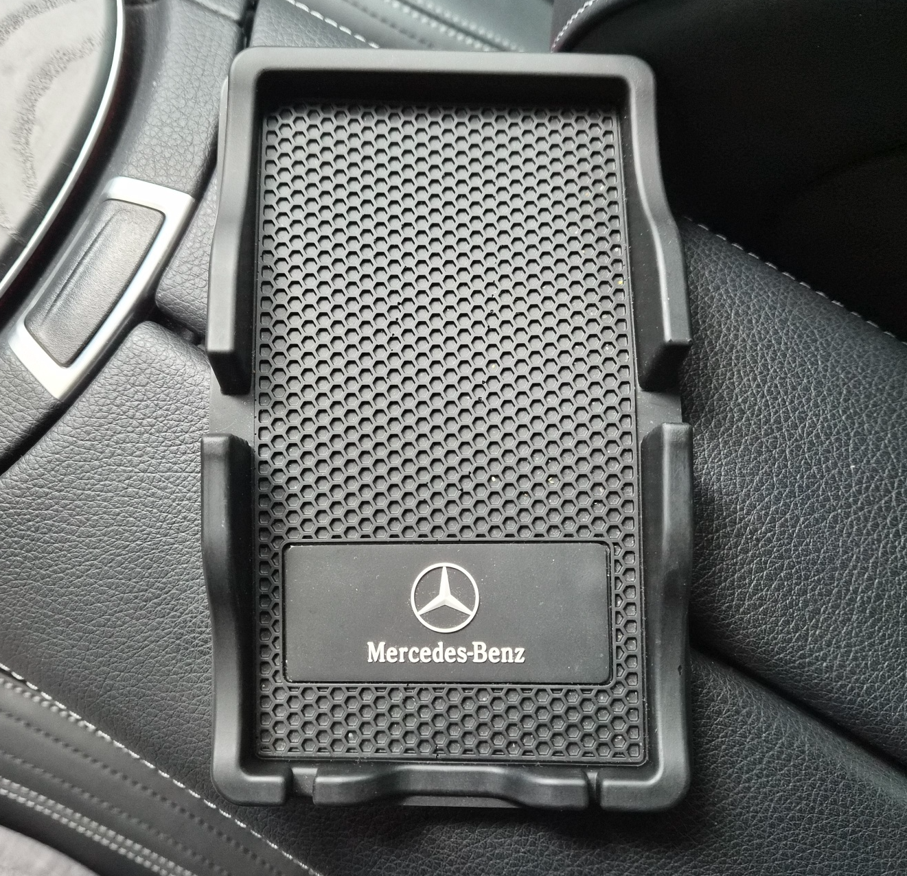 콘솔 위에 놓인 블랙 세미매트 논슬립 트레이 상단 샷—벌집 패턴과 Mercedes-Benz 로고 플레이트