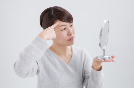 이마의 주름을 신경쓰는 여성.