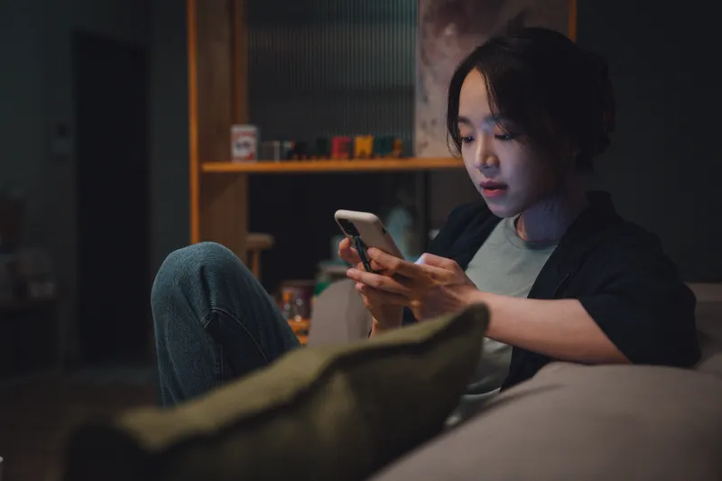 어느 실내를 배경으로 소파에 앉아 핸드폰으로 무언가 문자를 보내는 영화 타겟의 장수현