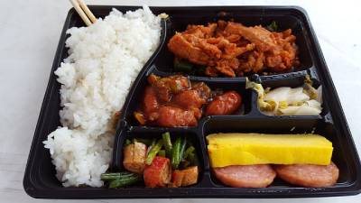 검은색 플라스틱 용기에 들어있는 밥과 반찬으로 구성된 한국식 도시락
