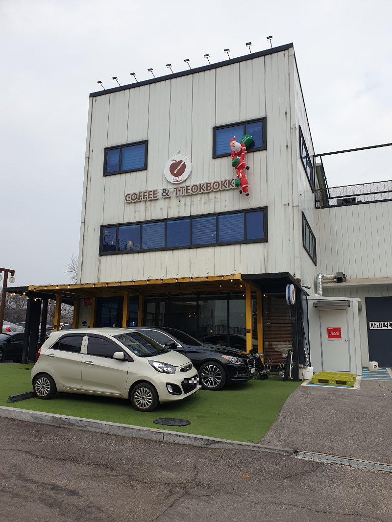 커피 앤 떡볶이라고 쓰인 간판이 있는 카페 전면. 산타 인형이 설치되어 있다.