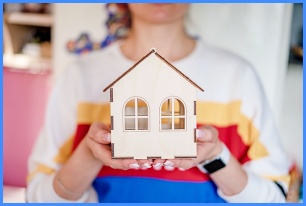 주택 모형을 들고 있는 사람