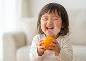 귤을 들고 환하게 웃는 어린이의 모습을 담아 밝고 행복한 이미지를 전달합니다.
