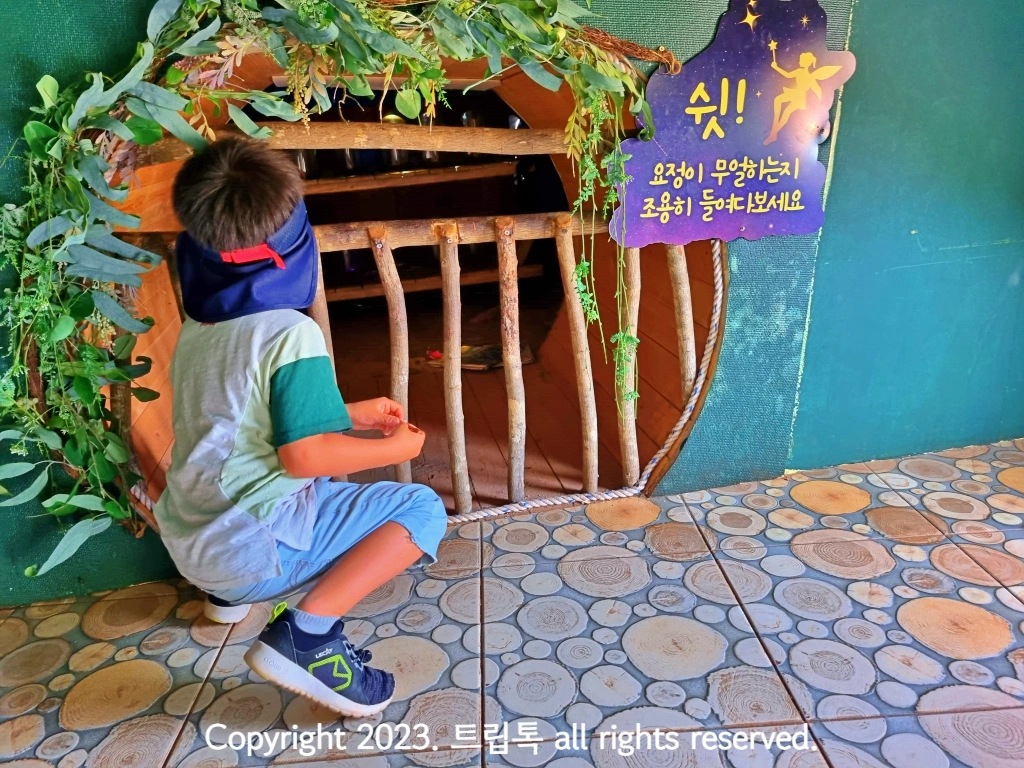 나무로 된 동그란 구멍을 들여다보는 아이