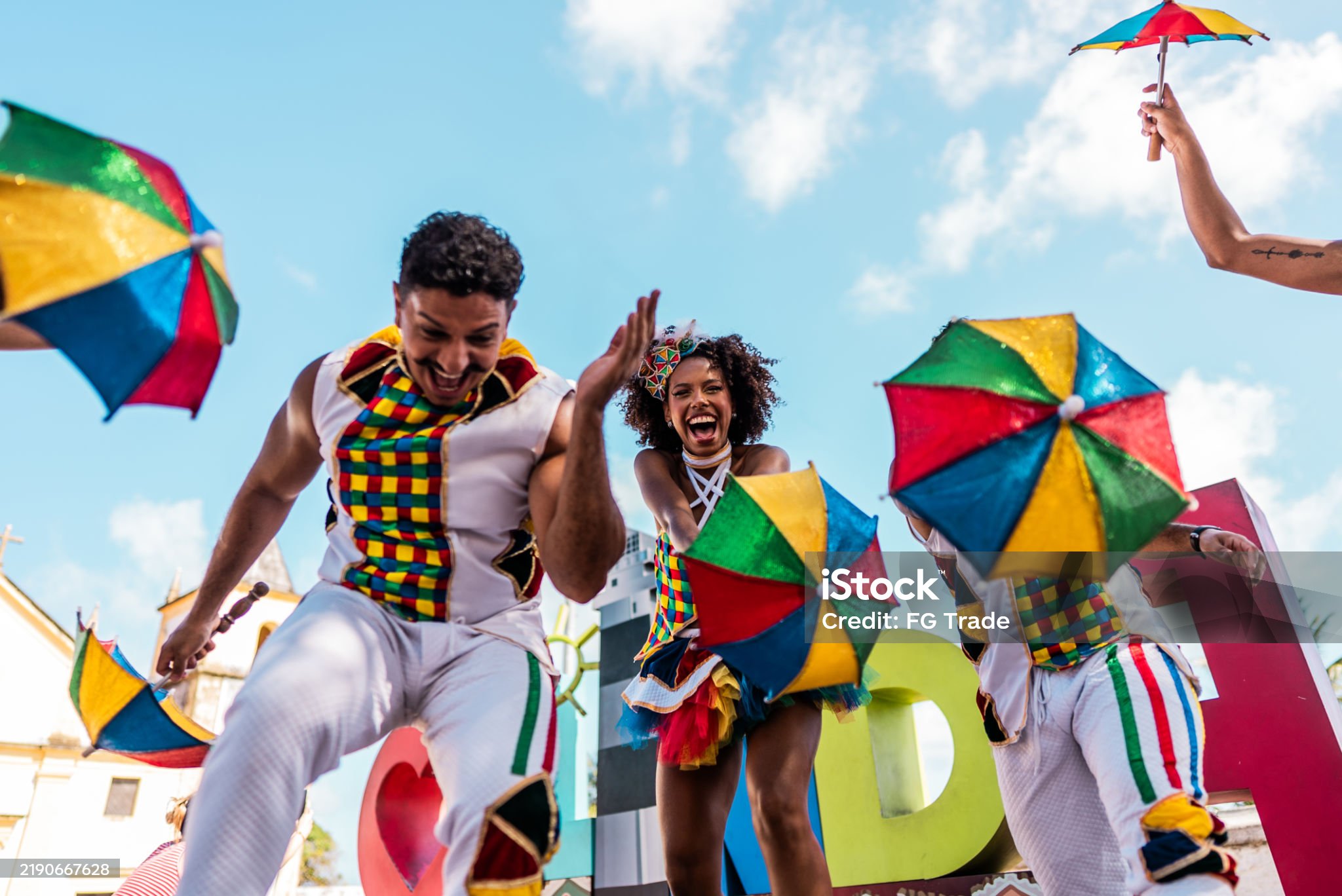 빨강 파랑 노랑 녹색으로 된 우산들 들고 사람들이 춤을추며 즐거워하는 사진입니다.