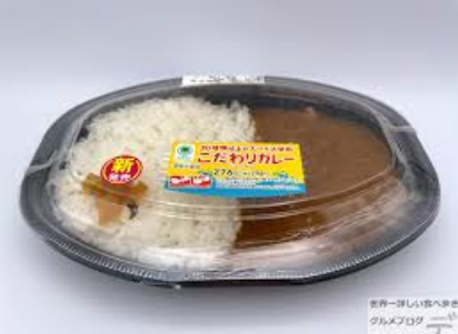 투명한 도시락 뚜껑 안으로 밥과 갈색 카레가 보인다.