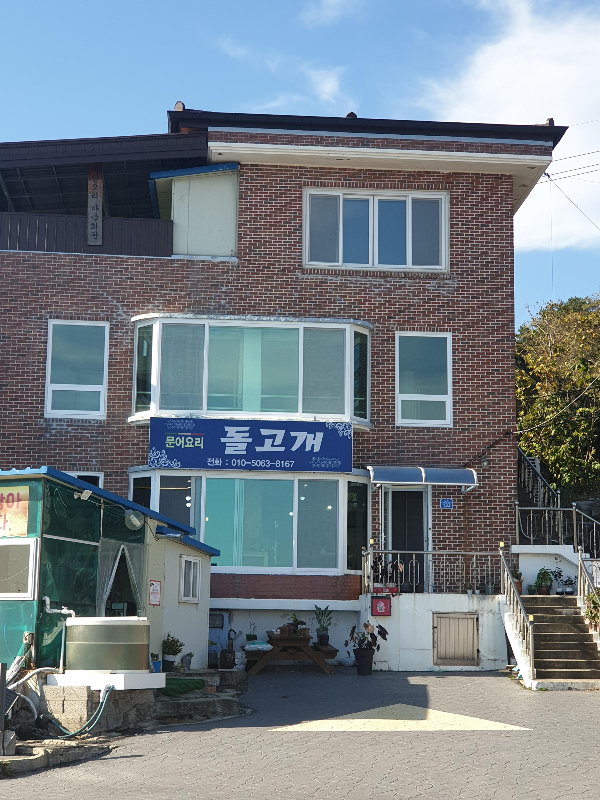 적벽돌로 된 3층 건물의 1층이 돌고개. 파란색 바탕의 흰색 글씨로 돌고개라고 쓴 간판이 보인다.