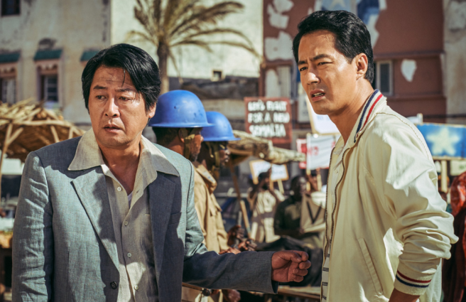 모가디슈 주인공 김윤석, 조인성이 한쪽을 심각한 모습으로 바라보고 있다