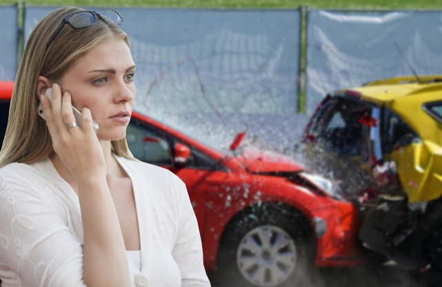 교통사고 현장을 배경으로 휴대전화로 통화 중인 여성 운전자.