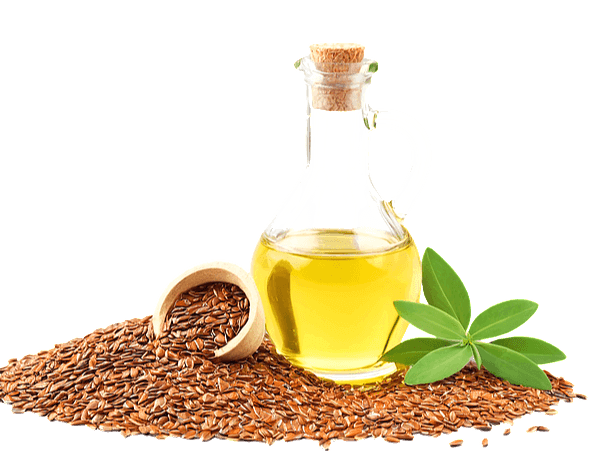 투명한 유리병에 노란색의 기름이 반쯤 있다. 병 주변에는 갈색의 씨앗들과 올리브 잎이 있다.