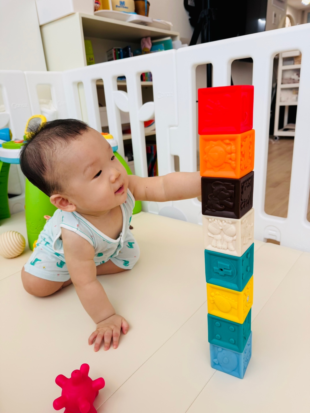 손을 뻗어 소프트블럭을 조심스레 무너뜨리는 아기