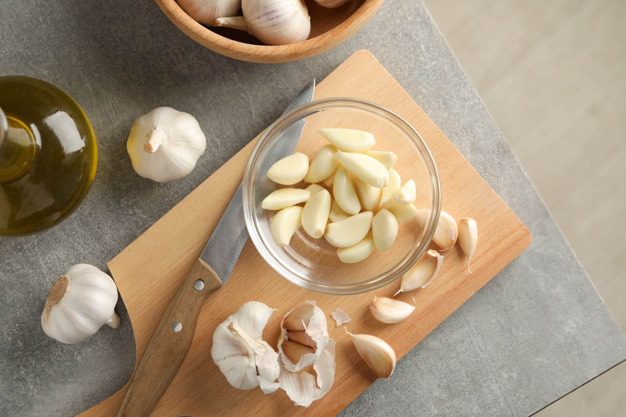 껍질 벗긴 마늘과 통마늘, 도마와 칼 위에 담긴 면역력 강화 식재료