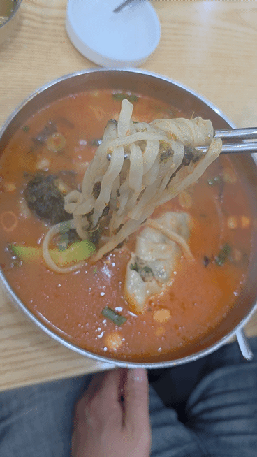 북촌손만두 얼큰칼만둣국 면을 젓가락으로 들어 올린 모습