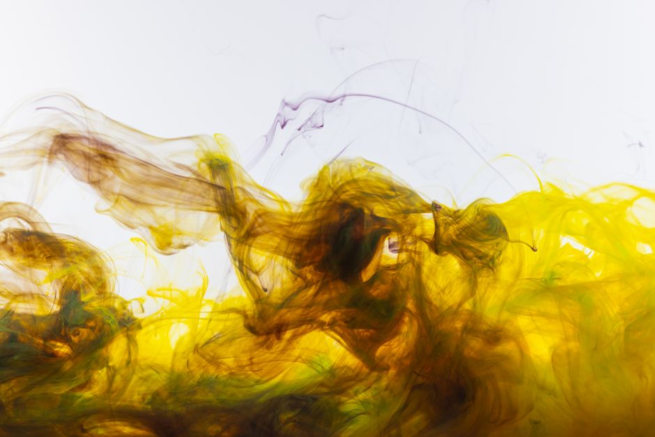 A mesmerizing abstract display of yellow and brown ink swirling dramatically in water.