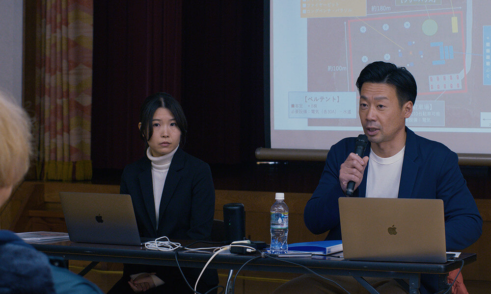 악은 존재하지 않는다 속 마을을 개발하려는 도시 직원들이 발표하는 모습