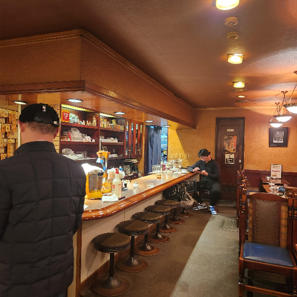 원목 가구로 된 클래식한 카페 내부. 바형 테이블과 일반 테이블이 모두 있다.