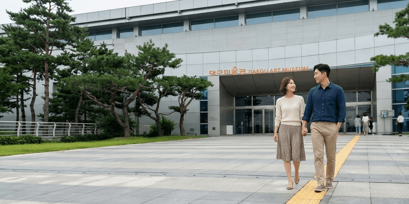 대구미술관 DAEGU ART MUSEUM 간판이 보이는 현대식 건물 입구와 넓은 석재 광장, 양옆으로 소나무가 심어진 맑은 날의 풍경