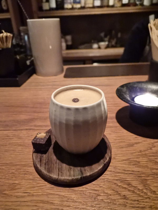 도자기 컵에 나온 누룽지 프레소. 위에 원두 한 알이 올려져 있다.