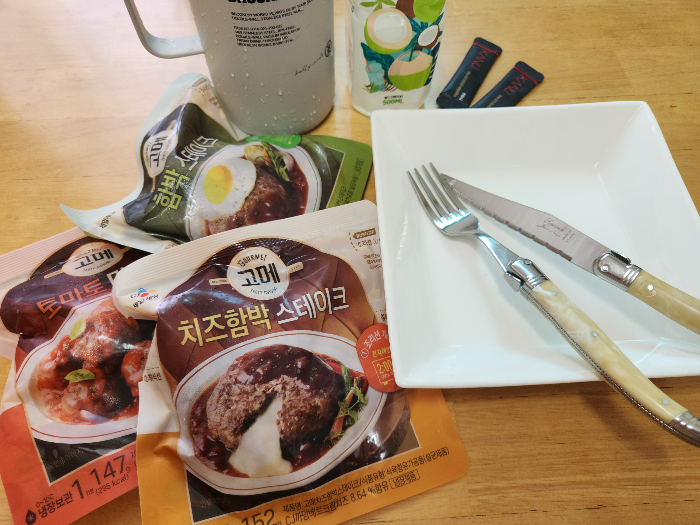 테이블 위에 미트볼, 스테이크와 컵, 포크, 나이프와 접시가 올려져 있다