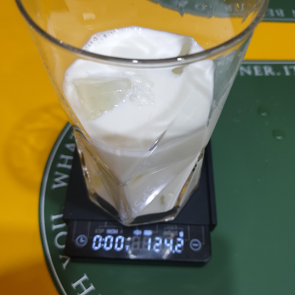 저울위에 얼음과 우유가 담긴 유리컵이 놓여있다. 저울은 124.2g을 가르킨다.