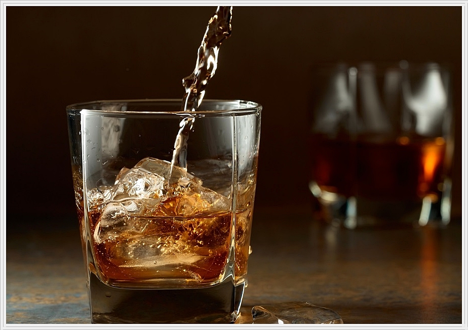 얼음이 든 잔 위로 술이 떨어지고 있는 모습