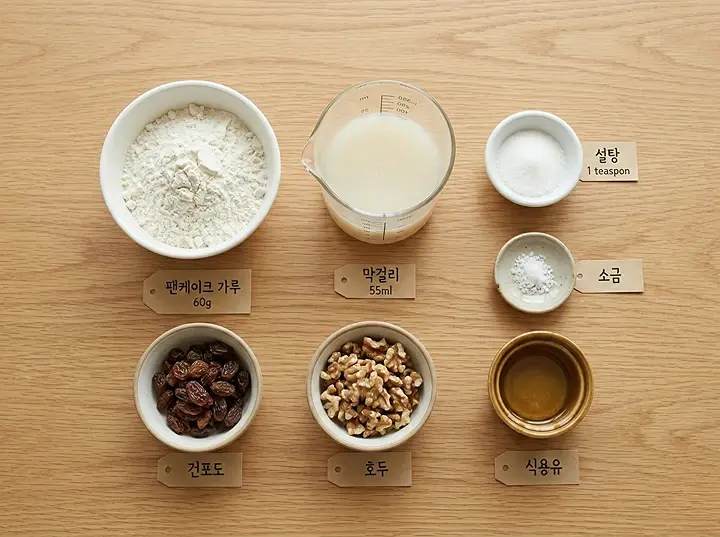 머그컵 술빵 재료 플랫레이 &mdash; 핫케이크가루 60g, 막걸리 55ml, 설탕, 소금, 식용유와 건포도&middot;견과류 토핑이 테이블 위에 계량되어 세팅된 모습