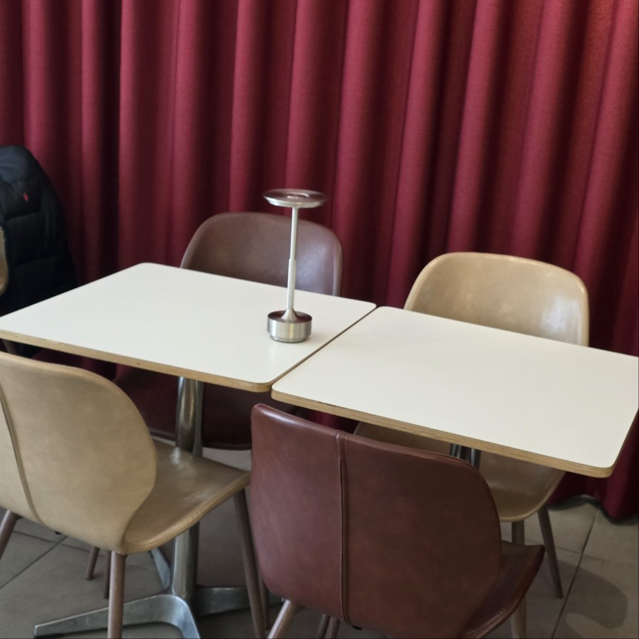 레드 커튼 앞에 배치된 카페 테이블과 의자, 조용한 분위기의 실내 좌석