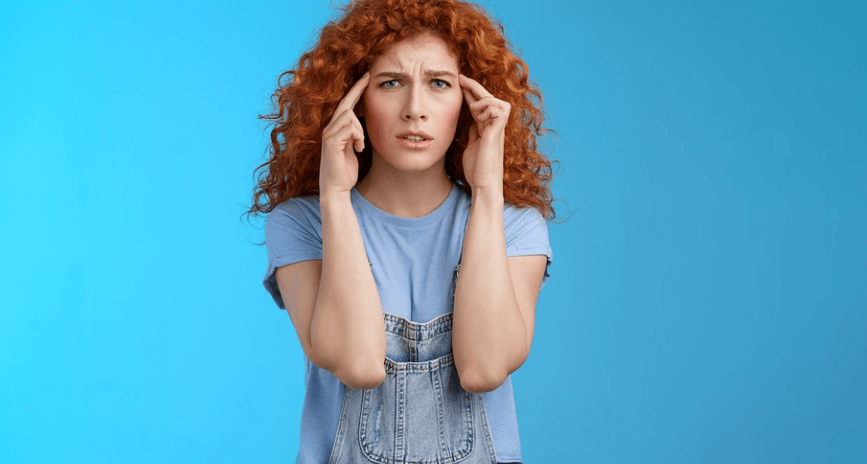 양 손가락을 이마에 되고 고통을 호소하는 여성