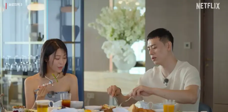 솔로지옥3-
호텔객실안 식탁위 음식과 음료수가 놓여있고 청소재 어깨가 없는 나시티를 입은 최혜선과 흰신반팔니트티를 입고 얘기하는 이관희