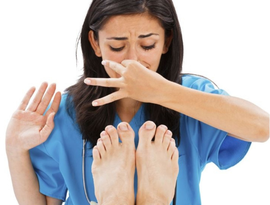 하늘색 의사복을 입은 여자 의사가 환자의 발을 보며 냄새 때문에 본인의 코를 손으로 잡고 괴로워 하고 있는 것을 찍은 사진