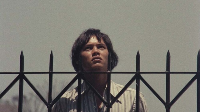 영화 《네온 불빛 속의 마닐라》에서 철창 너머를 올려다보는 젊은 남자의 얼굴. 도시의 빛은 화려하지만, 그 아래 깔린 계급과 착취의 현실은 냉혹하다. 자유는 늘 닿을 듯 멀리 있다.