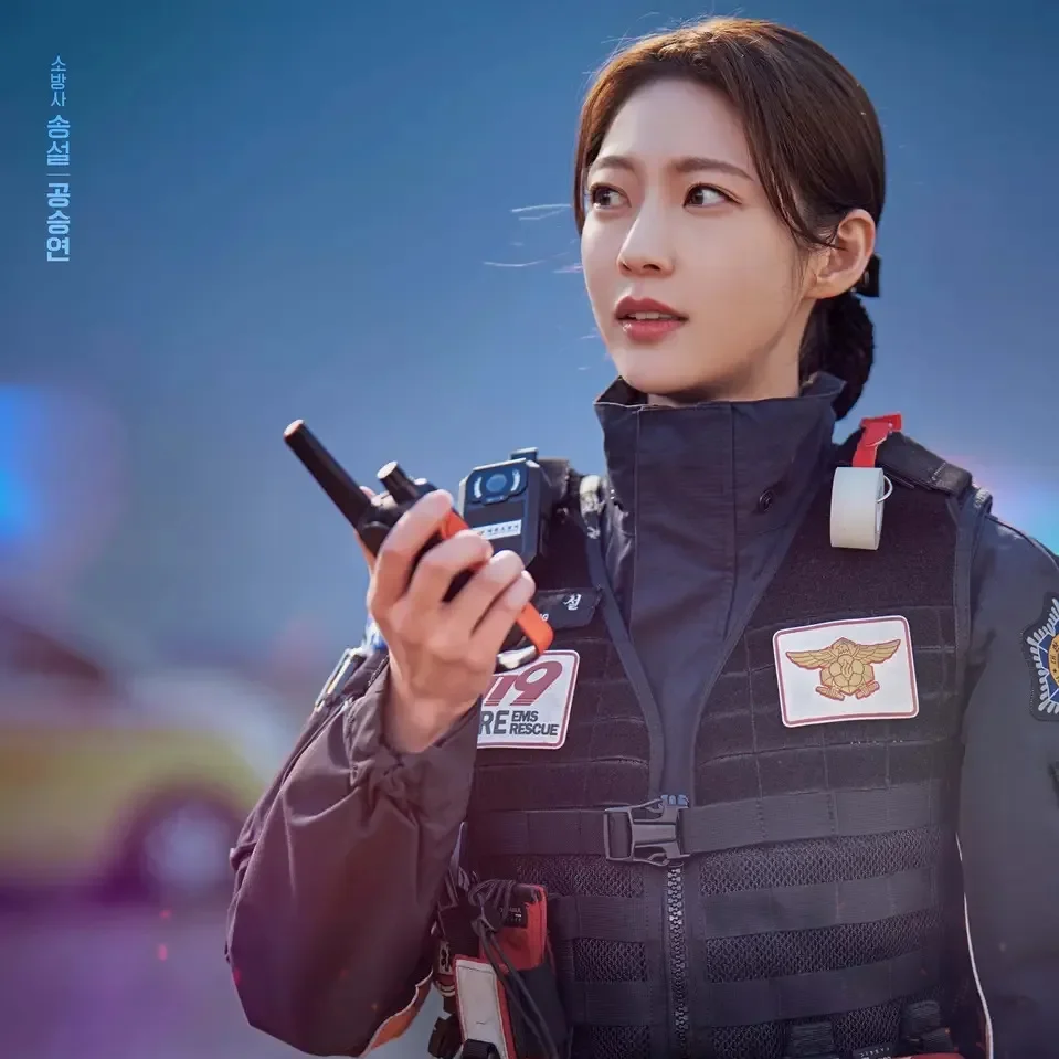 구급차를 배경으로 119 구급 요원 복장을 입고 무전기를 들고 있는 소방서 옆 경찰서 그리고 국과수의 송설