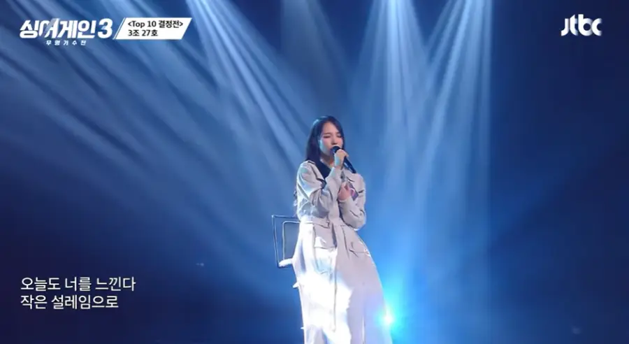 싱어게인3- 파란배경 흰옷을 입은 여자가 노래하는 모습을 멀리서 촬영한 모습