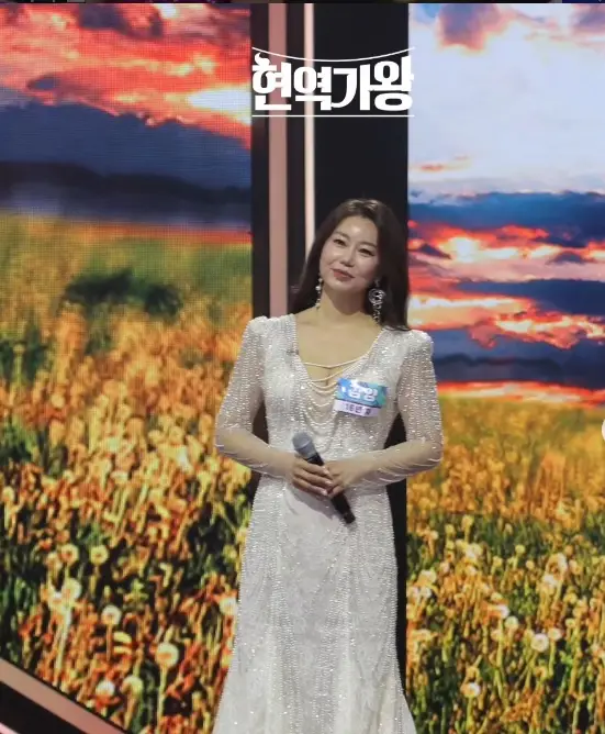 현역가왕- 무대위 흰색 가슴이 파인 원피스를 입고 마이크를 들고 서있는 김양