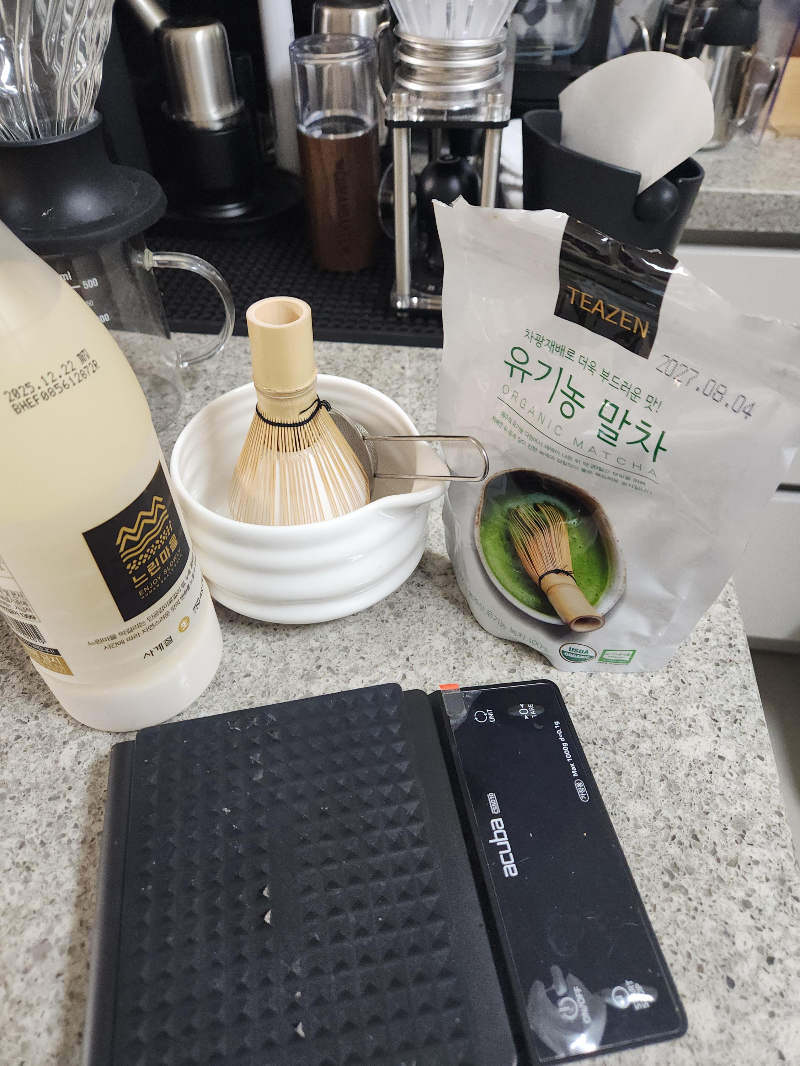 테이블 위에 차완, 막걸리, 유기농 말차 그리고 저울이 놓여 있다.