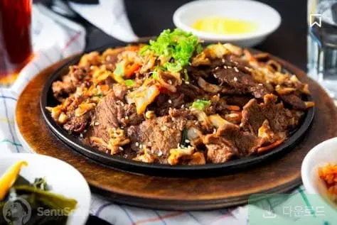 매콤한 양념의 돼지고기와 야채 제육볶음이 철판에 담긴 모습
